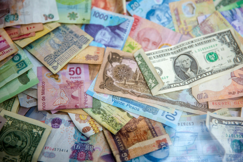 Billetes de distintos países sobre una mesa, referencia de presupuesto y precio